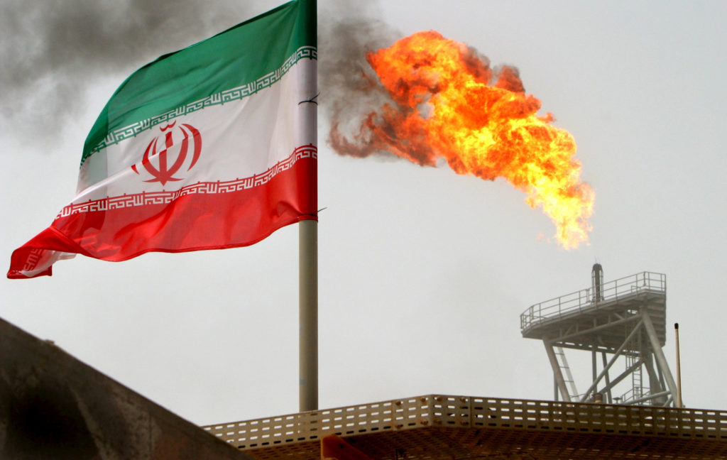A gas flare on an oil production platform is seen alongside an Iranian flag in the Gulf