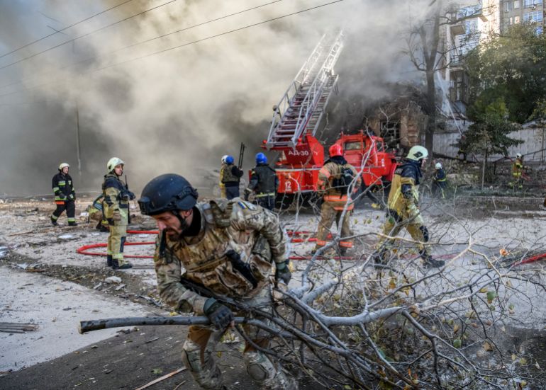 Firefighters help a local woman evacuate from a residential building destroyed by a Russian drone strike, which local authorities consider to be Iranian-made unmanned aerial vehicles (UAVs) Shahed-136, amid Russia's attack on Ukraine, in Kyiv, Ukraine October 17, 2022. REUTERS/Vladyslav Musiienko