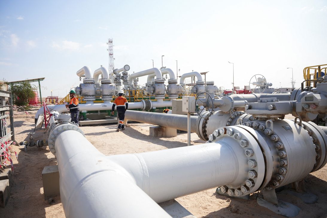 Workers walk across pipelines at the Rumaila oil field.