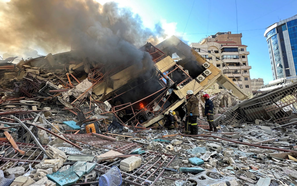 Members of the Lebanese Civil Defence inspect a damaged building after an Israeli strike on Beirut's southern suburbs