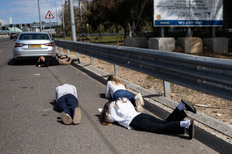 Israelis lie on the road to take cover during a siren following a barrage of missiles from Iran