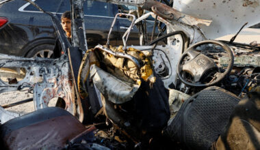 Palestinians inspect the site of an Israeli airstrike targeting a police vehicle in the central Gaza Strip
