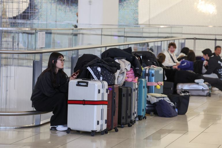 People sit at Terminal B of LaGuardia Airport, after an Air Canada Express jet collided with a ground vehicle,