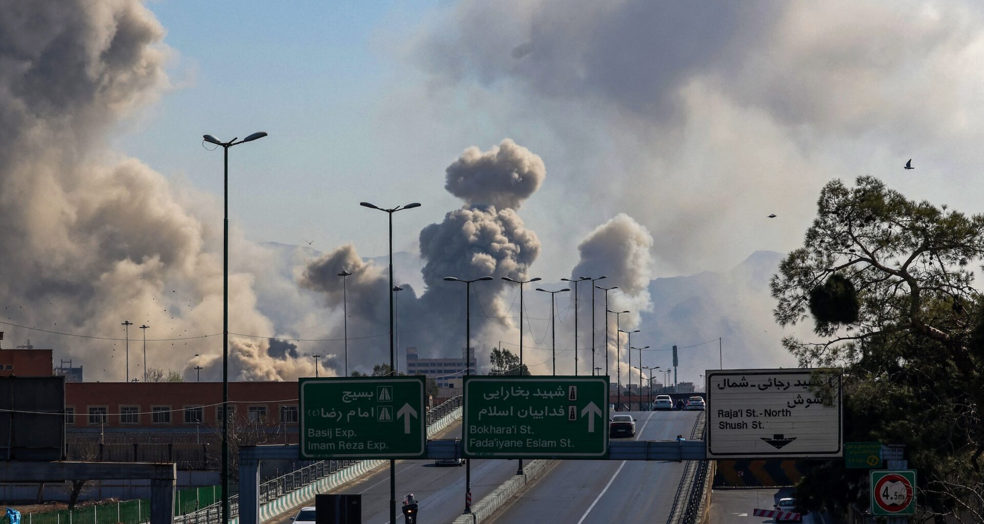Motorists drive along an expressway as plumes of smoke rise after strikes on Tehran on March 5, 2026.