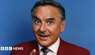 Bob Monkhouse in a suit pointing at the camera