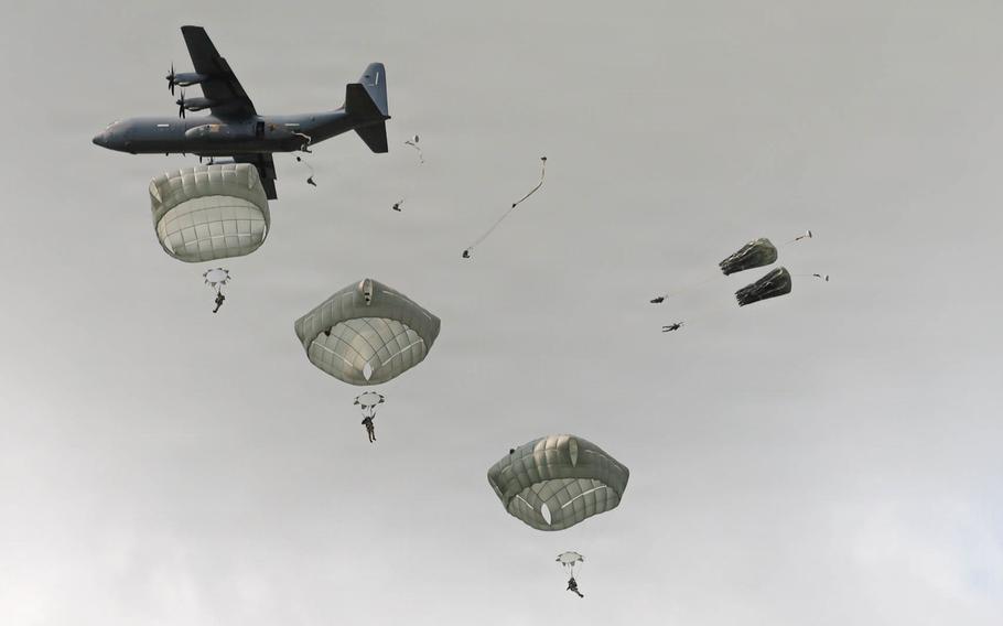 Paratroopers jump from an aircraft.
