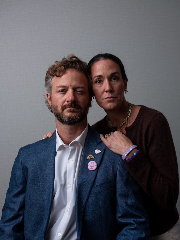 A couple pose against a neutral gray backdrop for a studio portrait.