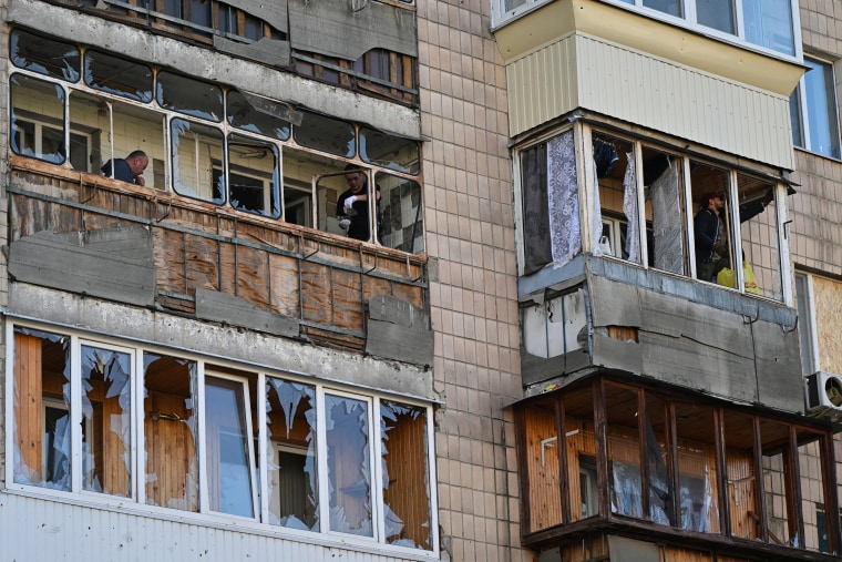 People clear shattered glass on balconies in a damaged residential building at a site of a strike in the town of Brovary, near Kyiv, following a Russian missile and drone attack, on March 14.