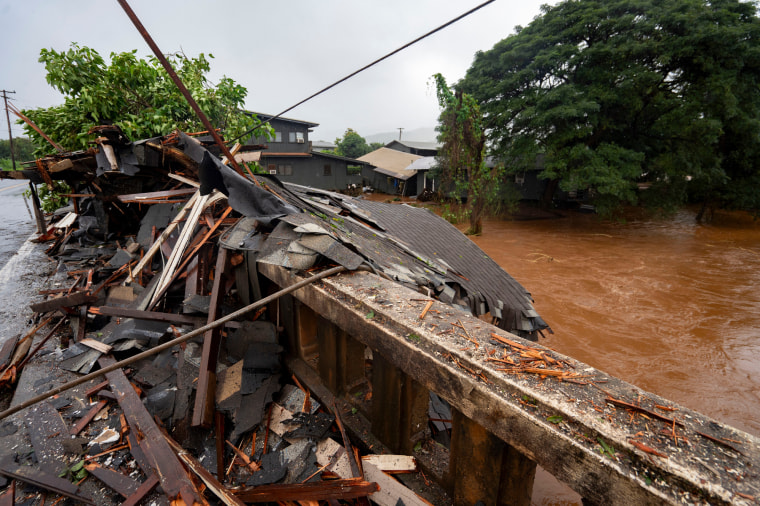 Broken boards and sections of roofing clustered against a bridge. 