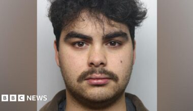 Kyran Smith mugshot. He has dark hair and dark stubble.