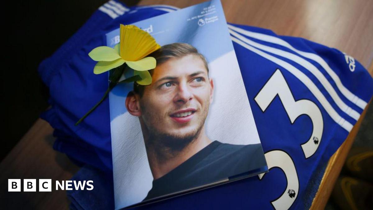 Flowers and football tops and scarves on the ground, surrounding a photograph of a young man, on the front of a magazine entitled "Bluebird".