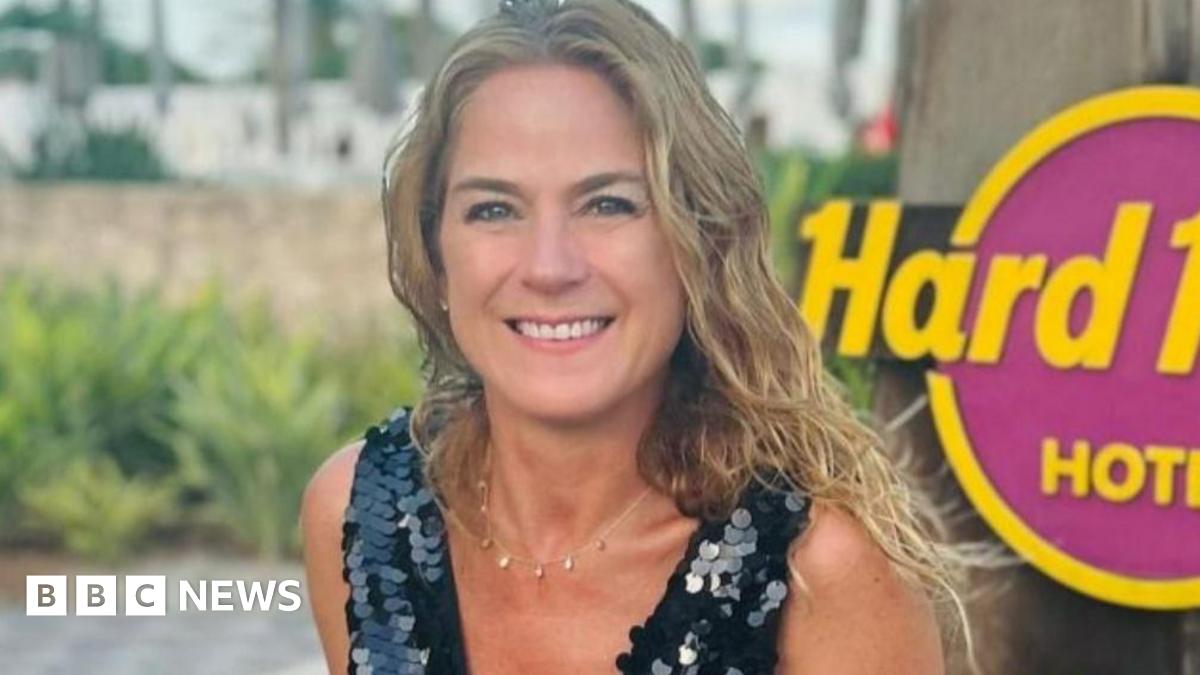 A woman in a black sequinned top on holiday against a Hard Rock sign