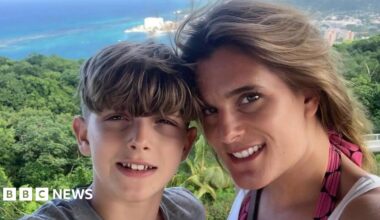 Julian Sweeney and his mother, Ellen Roome. They both have light brown hair and are pictured overlooking a view of trees and sea. Both of them are looking at the camera and smiling.