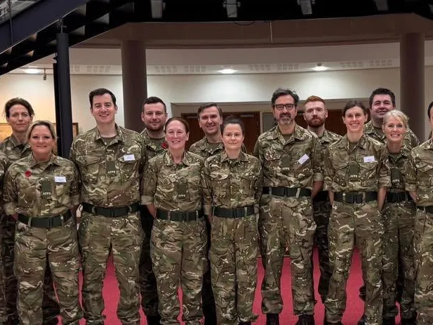 Joani Reid MP (10th from left) with members of Britain's Armed Forces in camouflage uniforms.