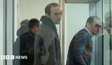 Martin Ryan (centre) looking to his right inside a glass prison cell where there are three other men also inside