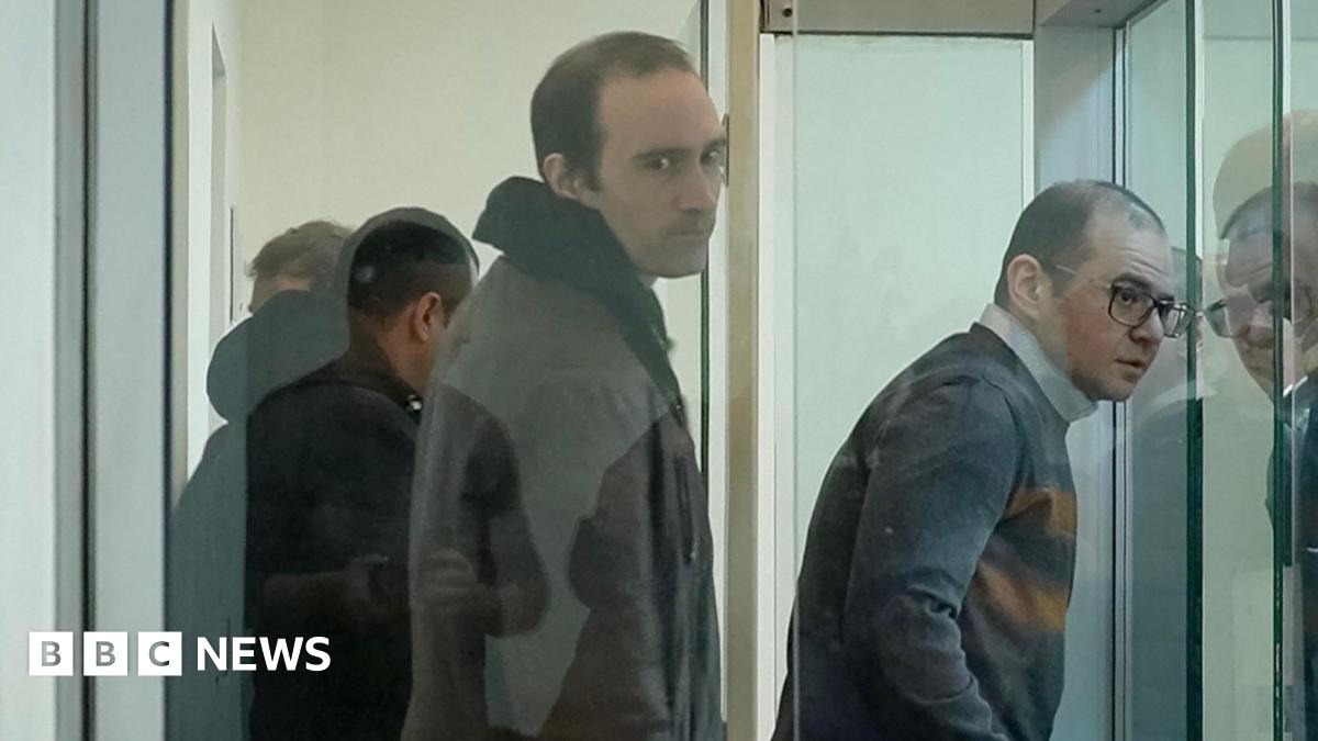 Martin Ryan (centre) looking to his right inside a glass prison cell where there are three other men also inside