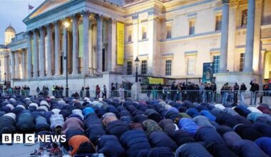 Dozens of people bowed in prayer, as the sun sets over the National Gallery building in Trafalgar Square