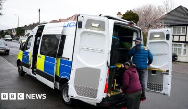 Four students walking side-by-side wearing blue face masks. Two boys on the left of the image, two girls on the right.