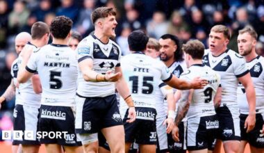 Hull FC players, in their white shorts and black shorts, celebrate a try against Catalans Dragons, with Davy Litten in the foreground urging the crowd to increase their support.