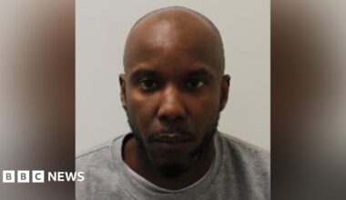 A mugshot of Owusu in a grey crewneck shirt. He stares blankly at the camera.