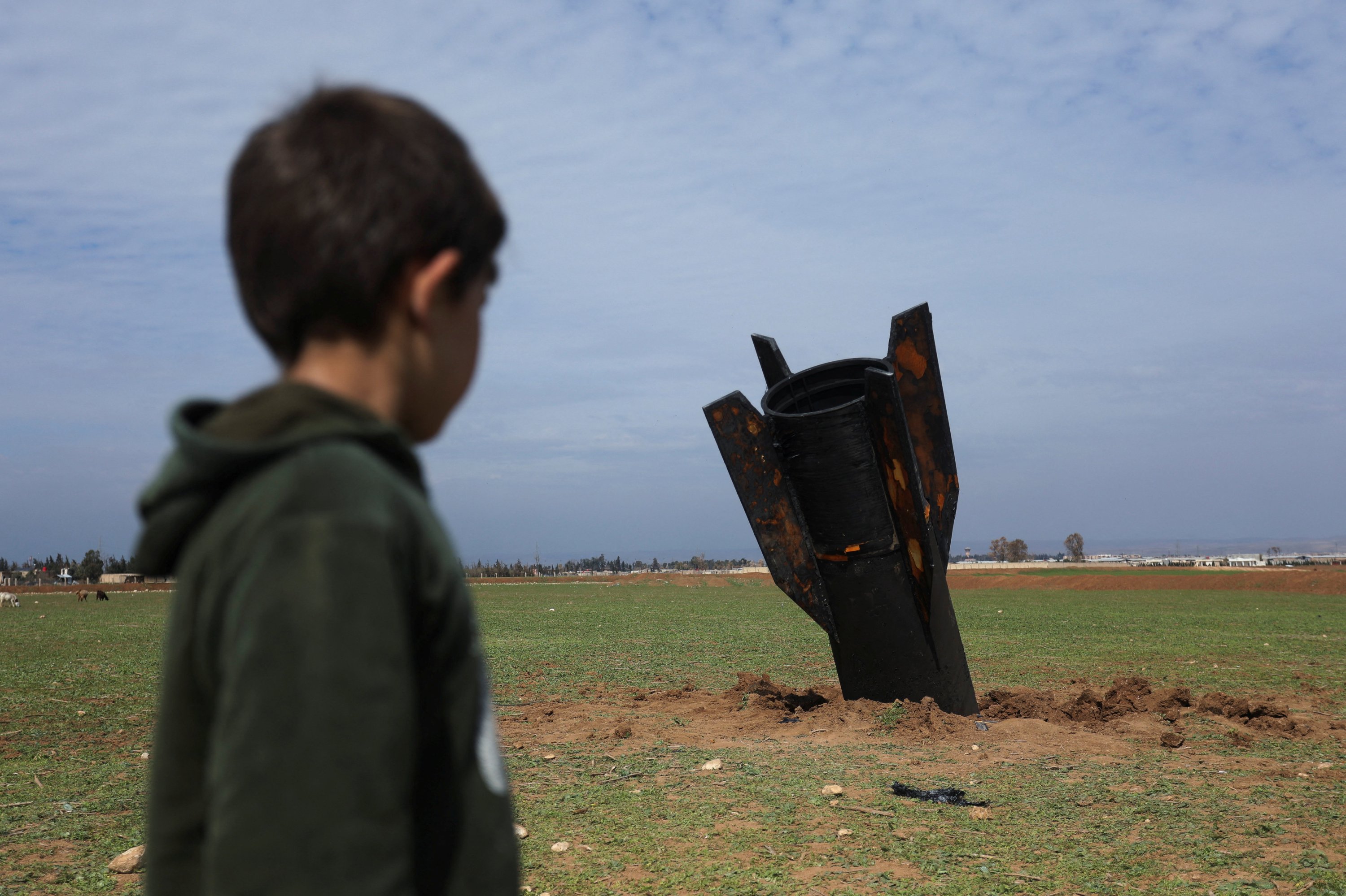 A child stands next to an Iranian missile after it fell near Qamishli International Airport, amid the U.S.-Israeli conflict with Iran, Qamishli, Syria, March 4, 2026. (Reuters Photo)