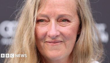 A close up of a middle-aged woman with long blonde hair, smiling at the camera.