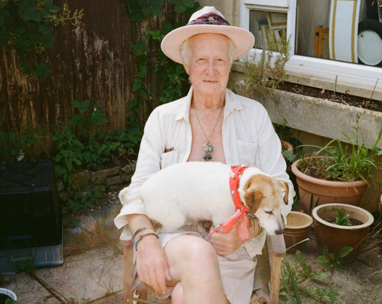 Peter Monro sitting outdoors with a dog on his lap.