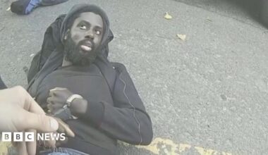 Four students walking side-by-side wearing blue face masks. Two boys on the left of the image, two girls on the right.