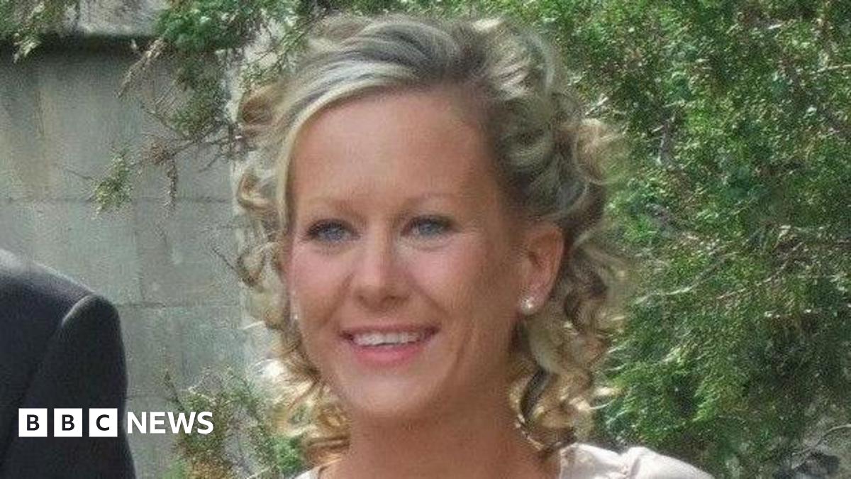 Gillian Morand stands outside in front of a tree. She has blonde curly hair.