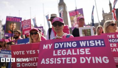Campaigners outside the houses of Parliament hold pink placards reading "My dying wish: Legalise assisted dying".