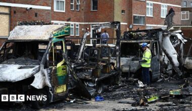 An official works among the burnt out ambulances at the scene of an antisemitic arson attack in the Golders Green neighbourhood of north London