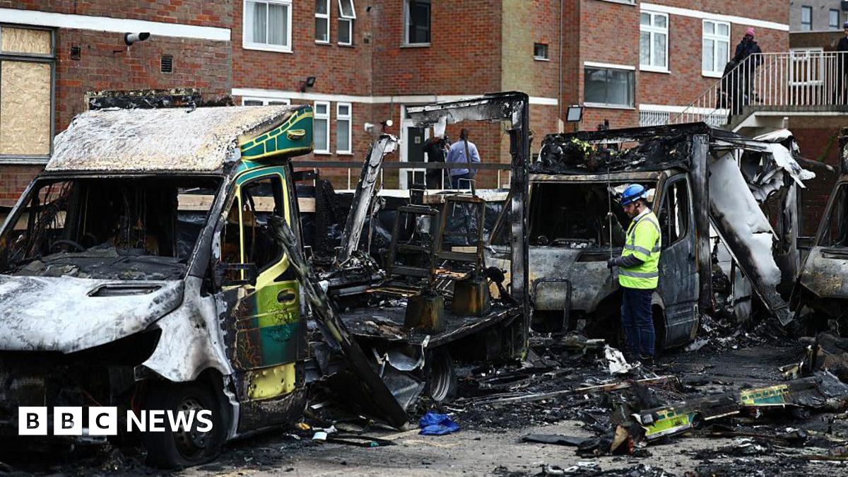 An official works among the burnt out ambulances at the scene of an antisemitic arson attack in the Golders Green neighbourhood of north London
