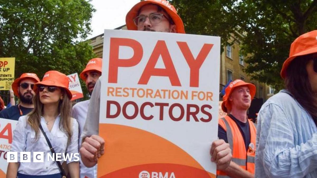 A person at a strike holds a poster which reads: "Pay restoration for doctors."