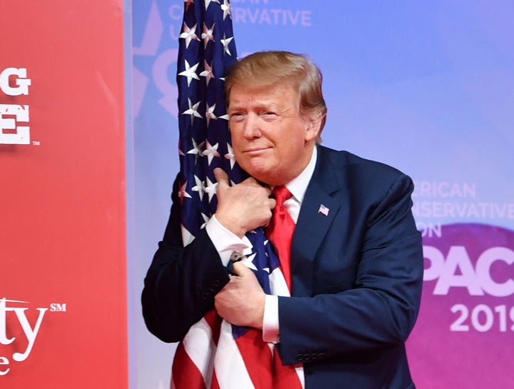 Trump looking like a high IQ individual while hugging the U.S. flag during an appearance at the Conservative Political Action Conference (CPAC) in 2019.