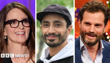 Headshots of Tina Fey - who is wearing a diamond necklace and black-rimmed glasses - Riz Ahmed - who is smiling and wearing a white hoodie and black cap - and Jamie Dornan who is wearing a blue shirt and suit jacket.