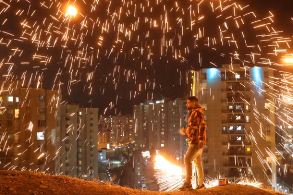 An Iranian man lights a firework during the Wednesday Fire celebration (Chaharshanbeh Suri in Persian) at a park in Tehran, Iran. (2024)