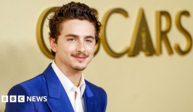 Timothee Chalamet in a bright blue suit and white shirt, posing in front of the word Oscars on a wall in large gold letters, at the 98th Oscars Nominees Luncheon at the Beverly Hilton Hotel on 10 February 2026