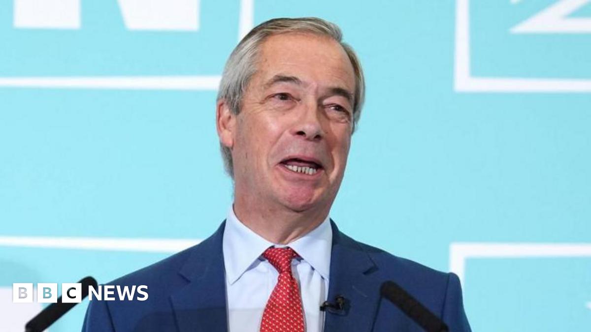 Reform Party leader Nigel Farage speaking during a Reform UK news conference. He is smiling and wearing a dark blue suit jacket, light blue shirt and red tie.