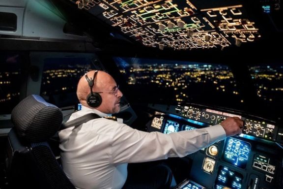 Mohammad Bagher Ghalibaf sits in a pilot’s cockpit during a night-time flight, reflecting his background as a former IRGC air force commander.