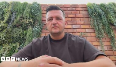 Gary Goldie looking right at the camera. He is wearing a brown T-shirt and is sitting in front of a brick wall.