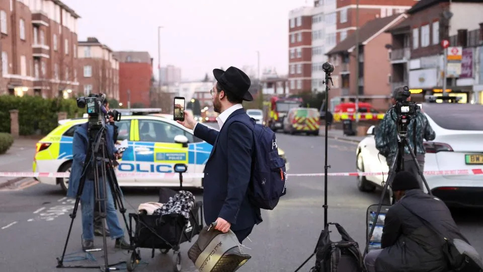 A man records using his mobile phone near the scene of the attack that police say is being treated as an antisemitic hate crime. - Hannah McKay/Reuters