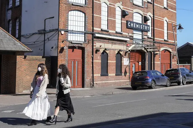 Pedestrians wearing face masks walk past Club Chemistry, a nightclub linked to a recent outbreak of meningitis