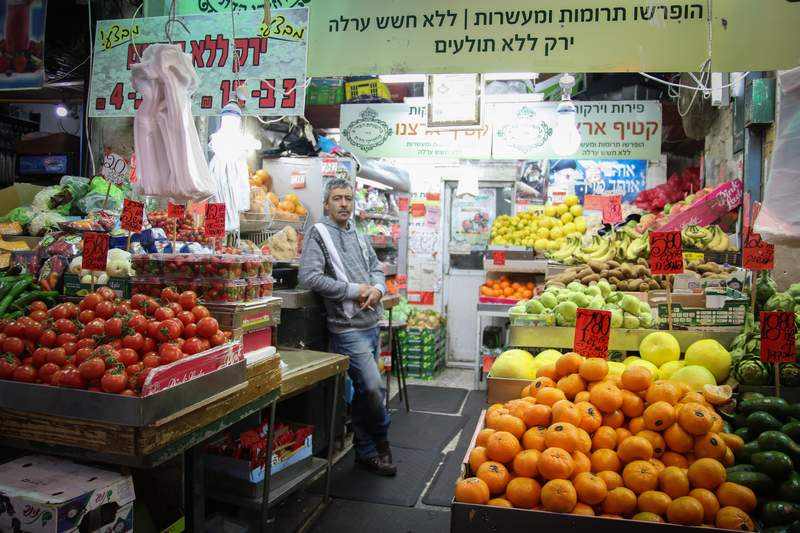 A man standing at a vegtable stand at the Mahane Yehuda market in Jerusalem, January 24, 2018. (photo credit: Liba Farkash/Flash90)