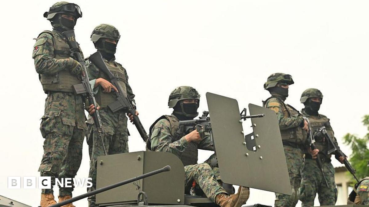 Five Ecuadorean soldiers stand atop an armoured vehicle at a command post in Guayas province. They are wearing camouflage uniforms, helmets and their faces are partly covered by black balaclavas. They are all heavily armed.