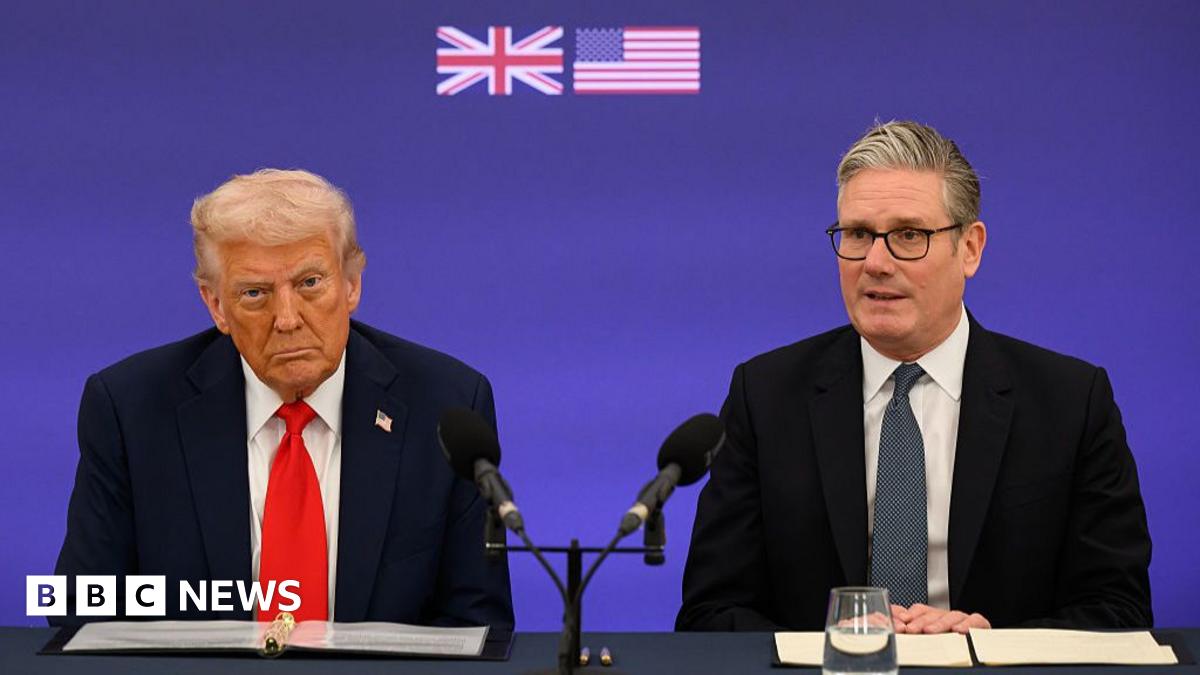 Donald Trump speaks with the media aboard Air Force One during a flight. He is wearing a black suit and red tie