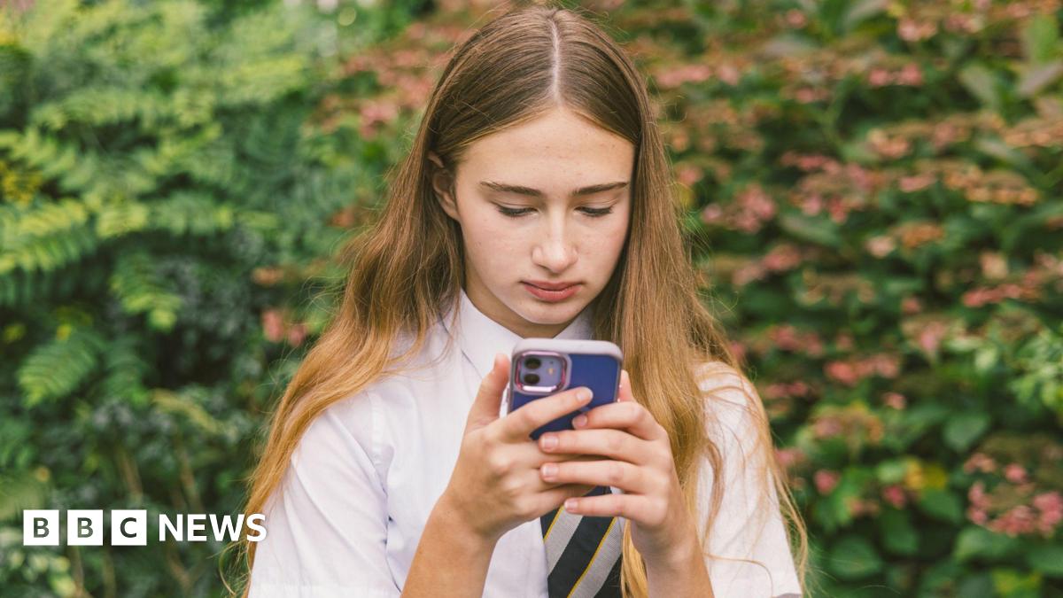 A teenage girl in school uniform stares at a phone