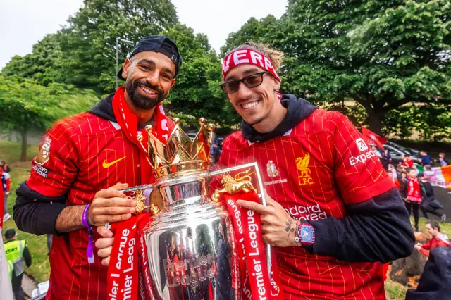Mohamed Salah and Kostas Tsimikas celebrate with the Premier League trophy