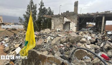 The yellow flag of the Hezbollah group hanging by the ruins of a house