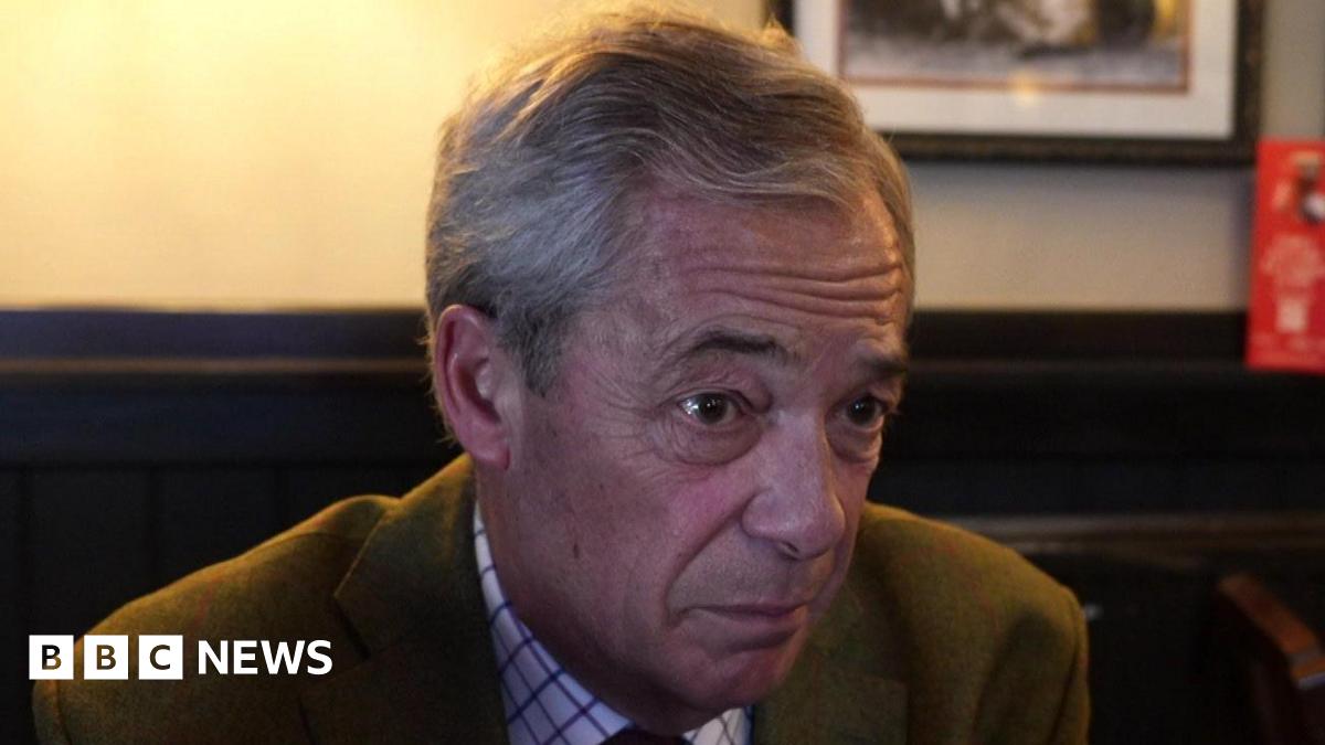 Nigel Farage - Reform UK leader - in a Leeds pub wearing a green jacket, checked white shirt, and maroon tie