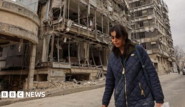 A woman walks next to bombed-out buildings on a street in Tehran (02/03/26)